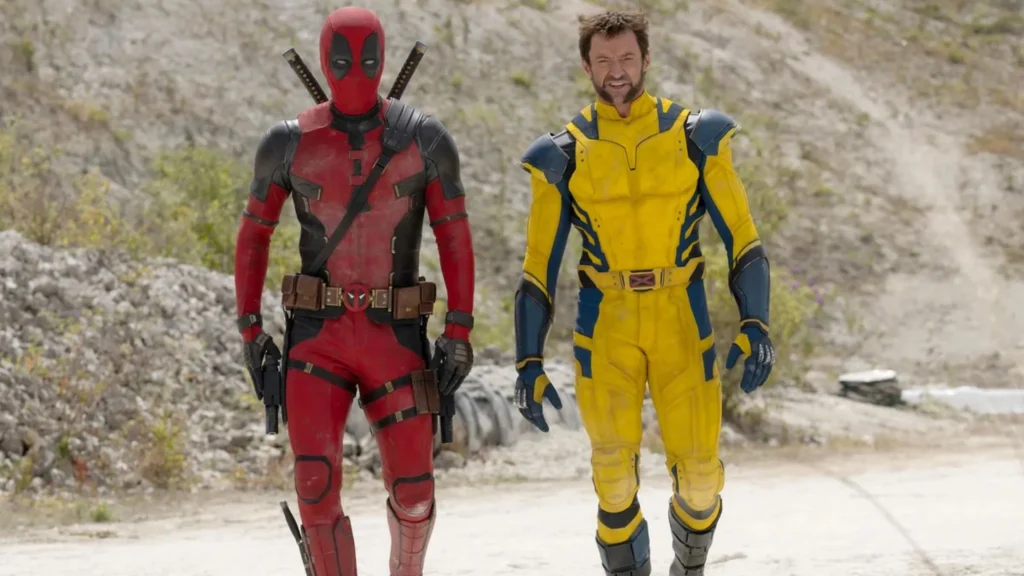 Deadpool and Wolverine in full costume walking side-by-side along a gravel path.
