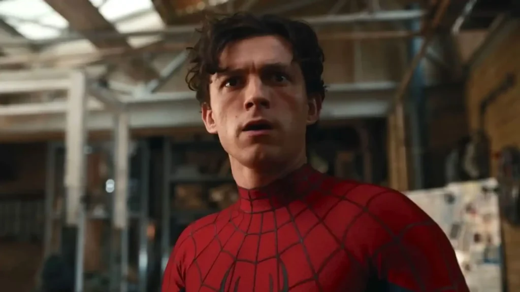 Close-up shot of Tom Holland as Spider-Man wearing his red suit looking stunned and concerned inside a workshop.
