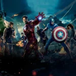 The Avengers team, including Iron Man, Captain America, Thor, Hulk, Black Widow, Hawkeye, and Nick Fury, standing combat-ready in a destroyed, burning city street.