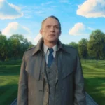Paul Bettany as Vision in human disguise, wearing a trench coat and suit while standing on a paved path in a surreal, perfectly manicured outdoor park setting.