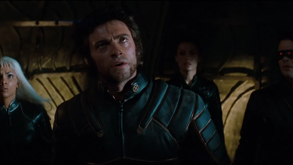 Hugh Jackman as Wolverine in black leather suit looking upward, flanked by Storm, Jean Grey, and Cyclops in X-Men (2000).