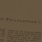 Close-up of a book page showing the heading "THE PHILOSOPHER'S STONE" and printed text detailing Nicolas Flamel.