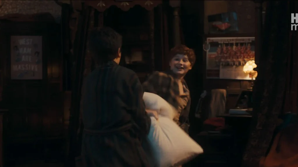 Two Hogwarts students having a pillow fight in a dark dormitory with a "West Ham Are Massive" poster visible on the wall.
