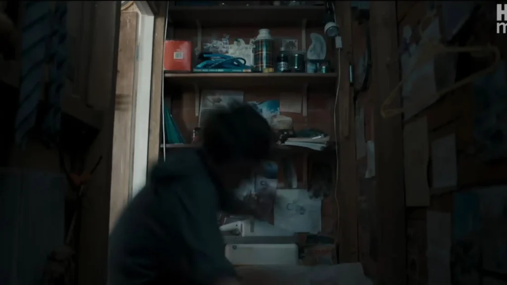 Wide view inside Harry's dark cupboard under the stairs featuring cluttered shelves and a small drawing taped to the wall.