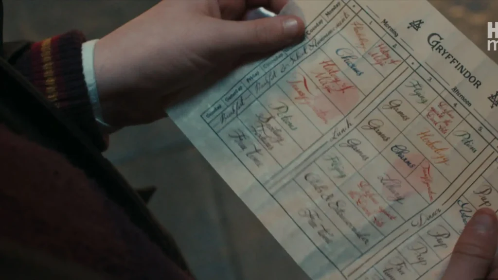 Hands holding a printed Gryffindor weekly class schedule showing subjects like History of Magic, Potions, and Charms.