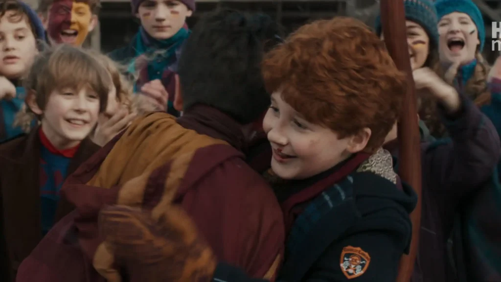 Ron Weasley with a bloody nose standing face-to-face against Draco Malfoy in the spectator stands during a Quidditch match.