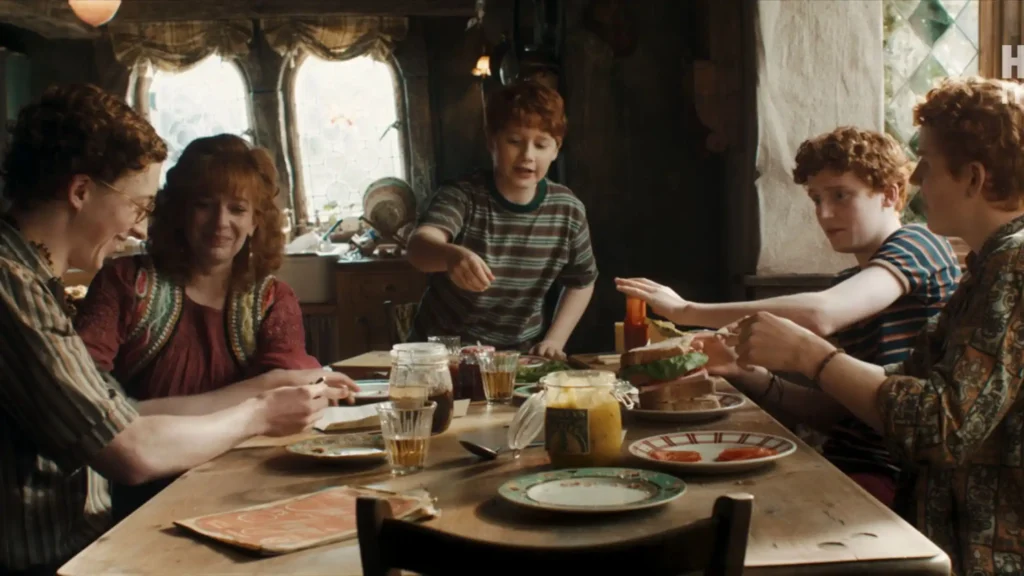The Weasley family kitchen with Mrs. Weasley, Percy holding a badge, and Fred and George spilling ketchup on a Hogwarts letter.