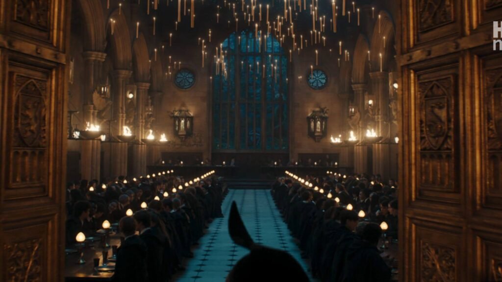 Long view down the center aisle of the Great Hall packed with seated students beneath hundreds of floating candles.
