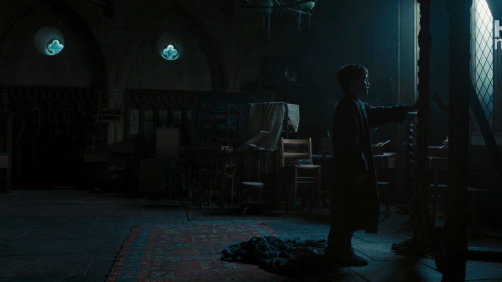 Silhouette of young Harry Potter standing alone at night in front of the tall, arched Mirror of Erised in an empty room.