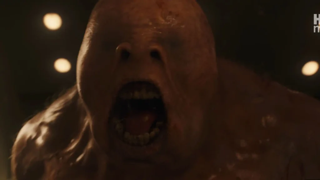 A massive, dark, slimy troll roaring inside a dim stone bathroom at Hogwarts.
